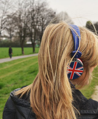 A young woman, in a park, wearing Union Jack headphone.